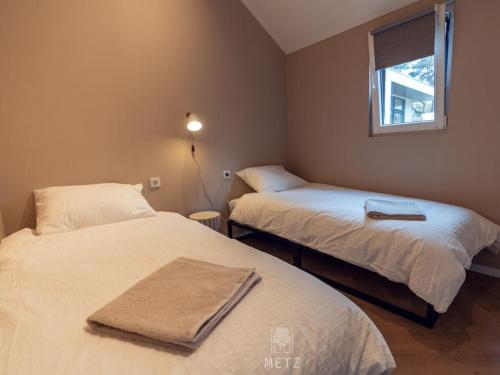 two beds in a small room with a window at Wellness Lodge with Hottub Haarle in Haarle