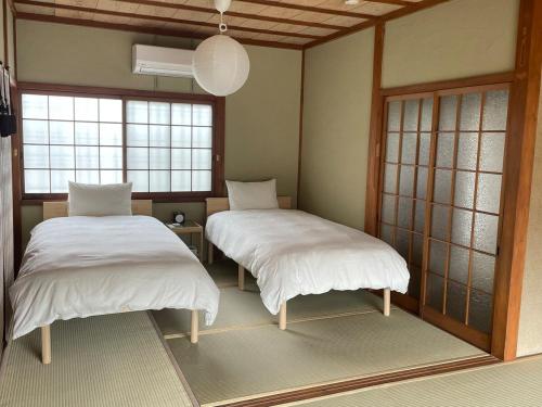 two beds in a room with two windows at MYOJI HOUSE 2 Traditional Japanese Stay in Katsuragi