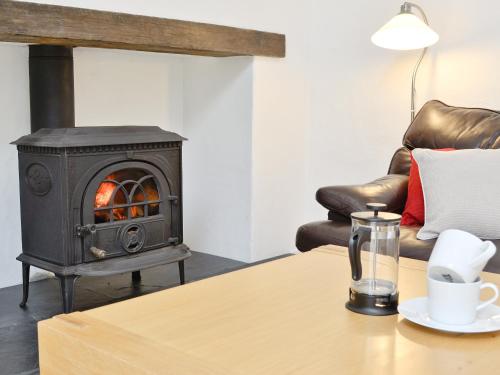 a wood stove in a living room with a table at Swallow Barn-Ow2 in Saint Twynnells