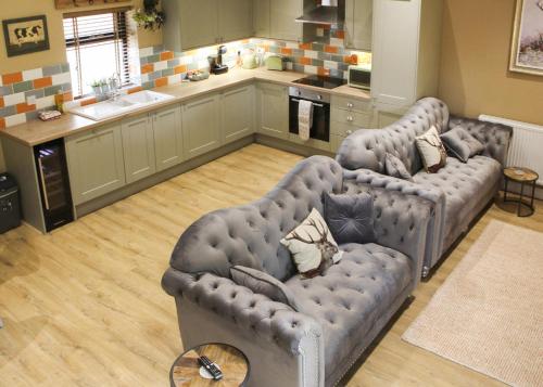 a living room with two couches and a kitchen at Beech Tree Park Cottages in Hatfield