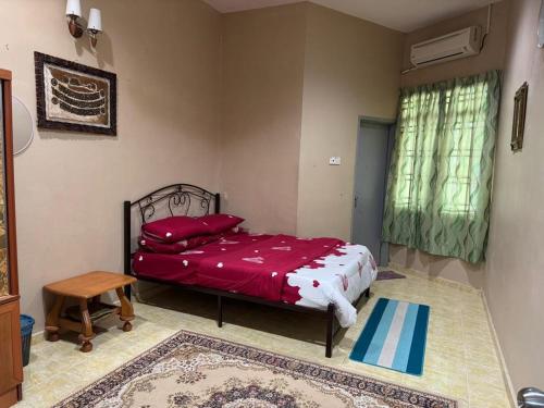 a bedroom with a bed with red sheets and a table at Labis Homestay Afina in Labis