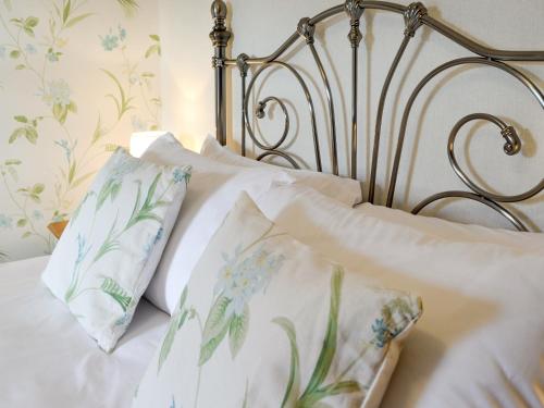 a bed with white sheets and blue and green pillows at Drumwherry By The Sea in Monreith