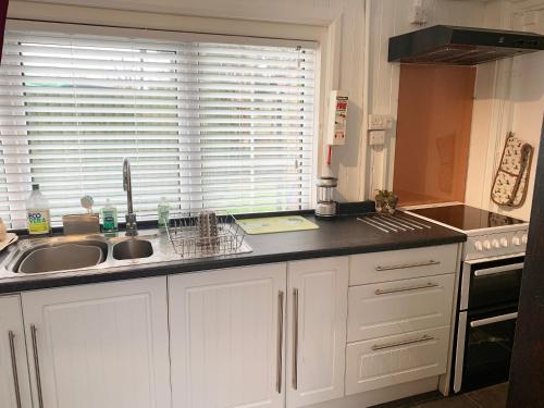 a kitchen with white cabinets and a sink and a window at Brookside in Ellingham