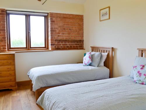 a bedroom with two beds and a brick wall at Partridge Barn in Sculthorpe