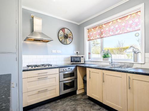 a kitchen with a stove and a sink and a window at Grayson Avenues in Pakefield
