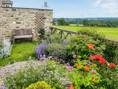einen Garten mit einer Bank und Blumen in der Unterkunft Snooty Fox Cottage in Hexham