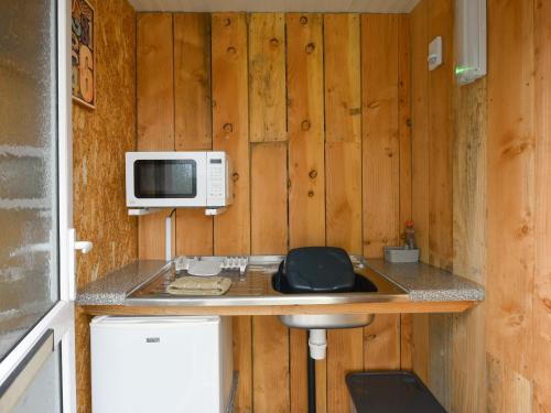 una cucina con bancone, forno a microonde e lavandino di The Hedgehog Pod - Uk50067 a Welshpool