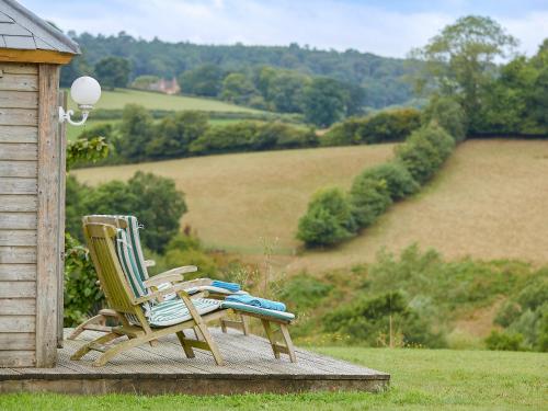 two chairs sitting on a deck with a view of a field at The Hay Barn in Sidbury