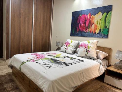 a bedroom with a bed with a painting on the wall at Appartement Haut Standing in El Jadida