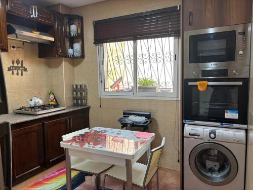 a kitchen with a table and a washing machine at Appartement Haut Standing in El Jadida