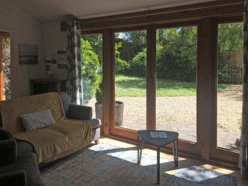 a living room with a couch and a glass door at Oaktree Cottage in Appledore