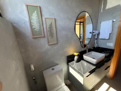 Un baño con lavabo, inodoro y espejo. en Cabanas 3quedas - Gonçalves-MG, en Gonçalves