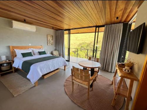 Un dormitorio con una cama y una mesa y un balcón. en Cabanas 3quedas - Gonçalves-MG, en Gonçalves