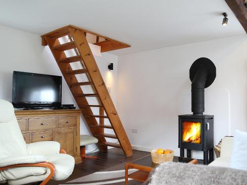 ein Wohnzimmer mit einem Holzofen und einem TV in der Unterkunft Stable Cottage in Icklesham