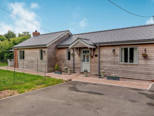 a wooden house with a driveway in front of it at Violet Cottage in Credenhill