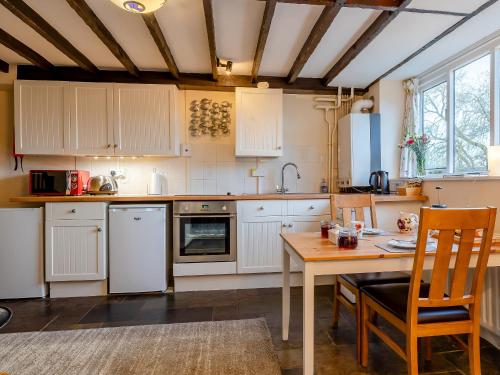 une cuisine avec des armoires blanches et une table en bois dans l'établissement Orchard Cottage - Uk30437, à Kingsbury Episcopi