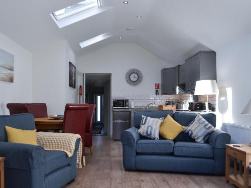 a living room with two blue couches and a kitchen at Little Tregarthen in Padstow