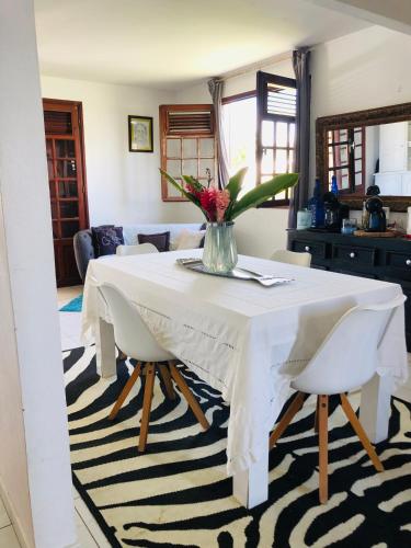 a white table with chairs and a vase of flowers at Chambre d'Hôtes Caïpi in Le Gosier