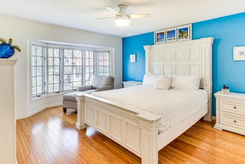 Un dormitorio con una cama blanca y una silla. en Steps to Ocean, Pool Access! Daytona Beach Gem, en Daytona Beach