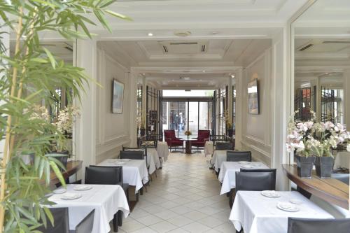 a restaurant with white tables and chairs and plants at Unic Renoir Saint Germain in Paris