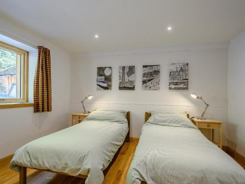 two beds in a room with two lamps and a window at Jack Strawbale House - Uk7521 in Strontian