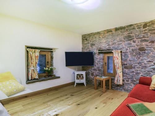 a living room with a stone wall and a flat screen tv at Horsecroft - Uk37462 in Dorstone