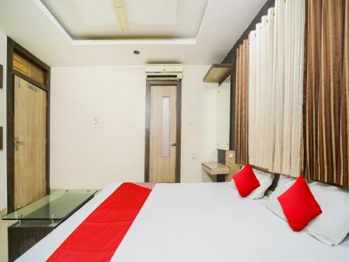 a bedroom with a large white bed with red pillows at Hotel O New Om Palace in Bhopal
