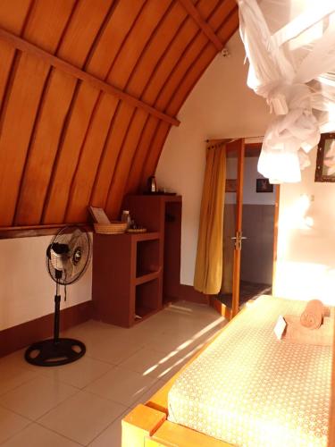 a room with a fan in the corner of a room at Rising Sun Bungalows in Gili Meno