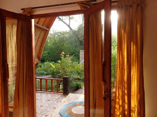 an open door leading to a patio with a garden at Rising Sun Bungalows in Gili Meno