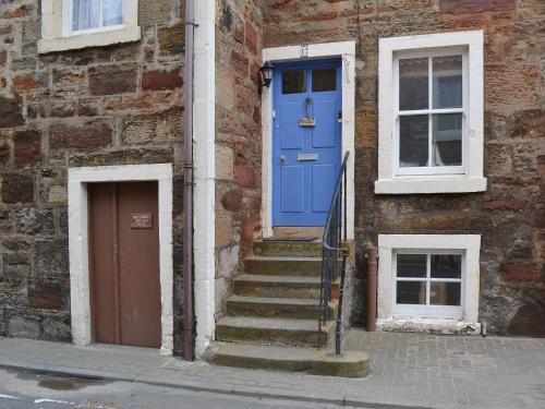 a blue door on the side of a brick building at Making Waves in Anstruther