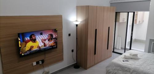 a bedroom with a flat screen tv on a wall at Lester Executive Studio Apartment 7 Minutes from United Nations & Embassies in Ruaka