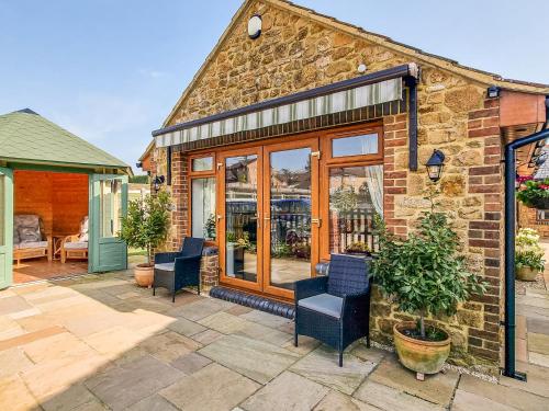 une maison en pierre avec des chaises et une terrasse dans l'établissement Whitney Cottage, à Broadway