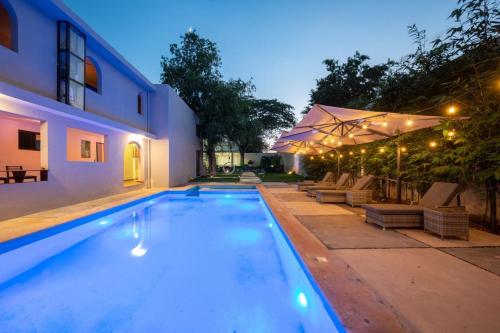 a swimming pool with chairs and umbrellas next to a house at Hotel Asia Star in Mérida