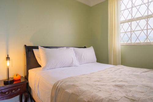 a bedroom with a bed with white sheets and a window at Musgrave AnneX- comfy 1 bedroom apartments in Kingston