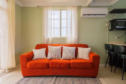 an orange couch in a living room with a window at Musgrave AnneX- comfy 1 bedroom apartments in Kingston