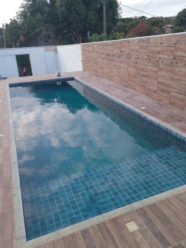 een zwembad met blauw water en een bakstenen muur bij Excelente casa in Búzios