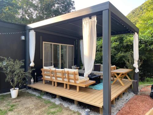a black gazebo with a table and benches at リバーサイドロッジ in Futtsu