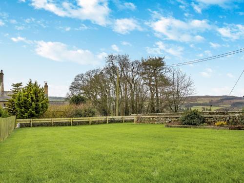 a large grassy yard with a fence and trees at Snowshill in Alnwick