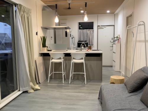 a kitchen with a sink and two bar stools at リバーサイドロッジ in Futtsu