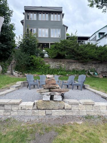 a firepit and chairs in a yard with a house at 2 Rivers Inn The Thousand Islands - LUXURY WATERFRONT WALKOUT in Gananoque