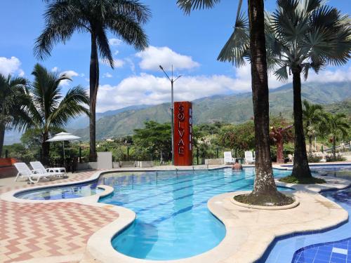 a pool with palm trees and mountains in the background at Solvae EcoHotel in San Jerónimo