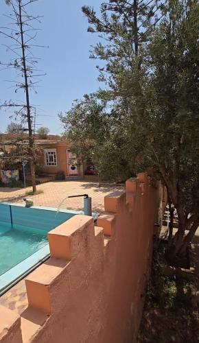 un mur de soutènement à côté d'une piscine et d'une maison dans l'établissement Ferme dar naciri, 