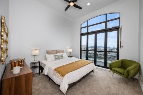 a bedroom with a large bed and a green chair at Oh Darling! Auckland CBD Penthouse in Auckland