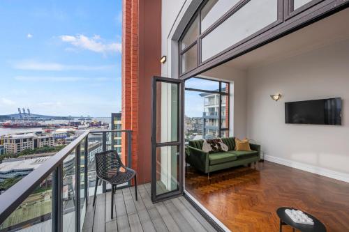 a room with a balcony with a couch and a tv at Oh Darling! Auckland CBD Penthouse in Auckland