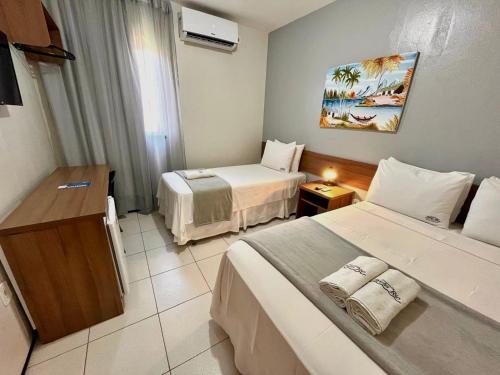 a hotel room with two beds and a television at Pousada Porto Rio in Parnaíba