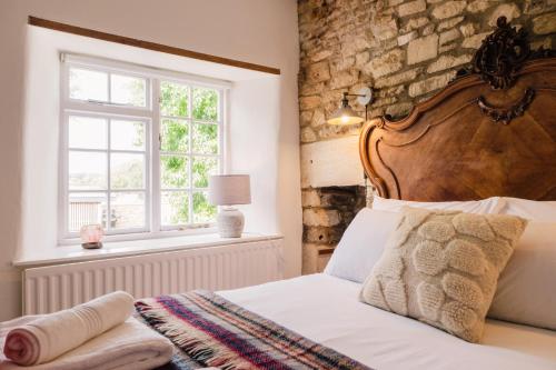 sypialnia z łóżkiem z drewnianym zagłówkiem i oknem w obiekcie Historic 3 Bedroom Cottage in the Cotswolds w mieście Idbury