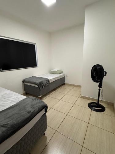 a room with two beds and a flat screen tv at Casa em Sete Lagoas - até 12 pessoas - Preço Justo in Sete Lagoas
