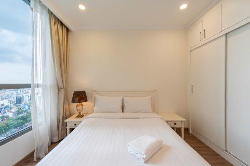 a white bedroom with a bed and a window at The Sun Avenue Apartment Moonlight in Ho Chi Minh City