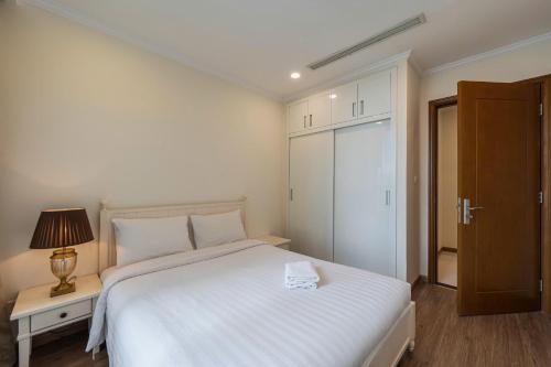 a bedroom with a large white bed with a lamp and a door at The Sun Avenue Apartment Moonlight in Ho Chi Minh City
