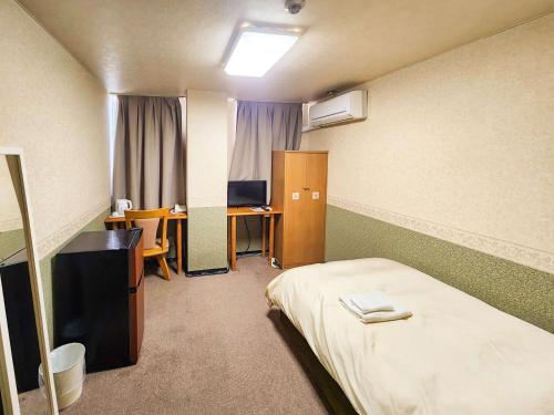 姫路市にあるホテル姫路ヒルズのベッドと机とパソコンのある部屋